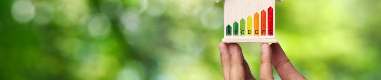 Concepts for evaluating energy efficiency in homes. Human hand holding a model house model and energy saving charts in home models On a Green background.