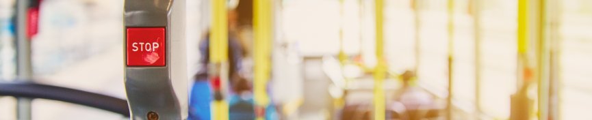 Red button STOP on the bus. Bus with yellow handrails and blue seats. Photo with the sun effect, glare on the lens from the light. Spacious interior of the bus, bright button with focus. Red button STOP on the bus. Bus with yellow handrails and blue seats. Photo with the sun effect, glare on the lens from the light. Spacious interior of the bus, bright button with focus.