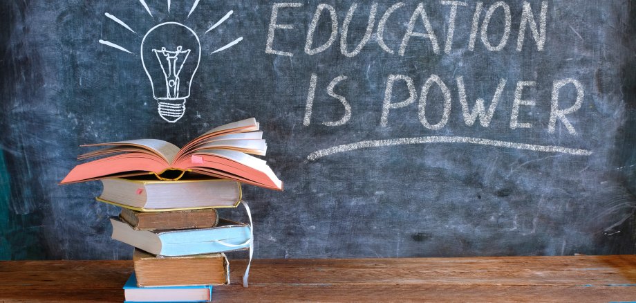 books and blackboard with drawing of a lightbulb and slogan education is power,learning,knowledge,back to school concept