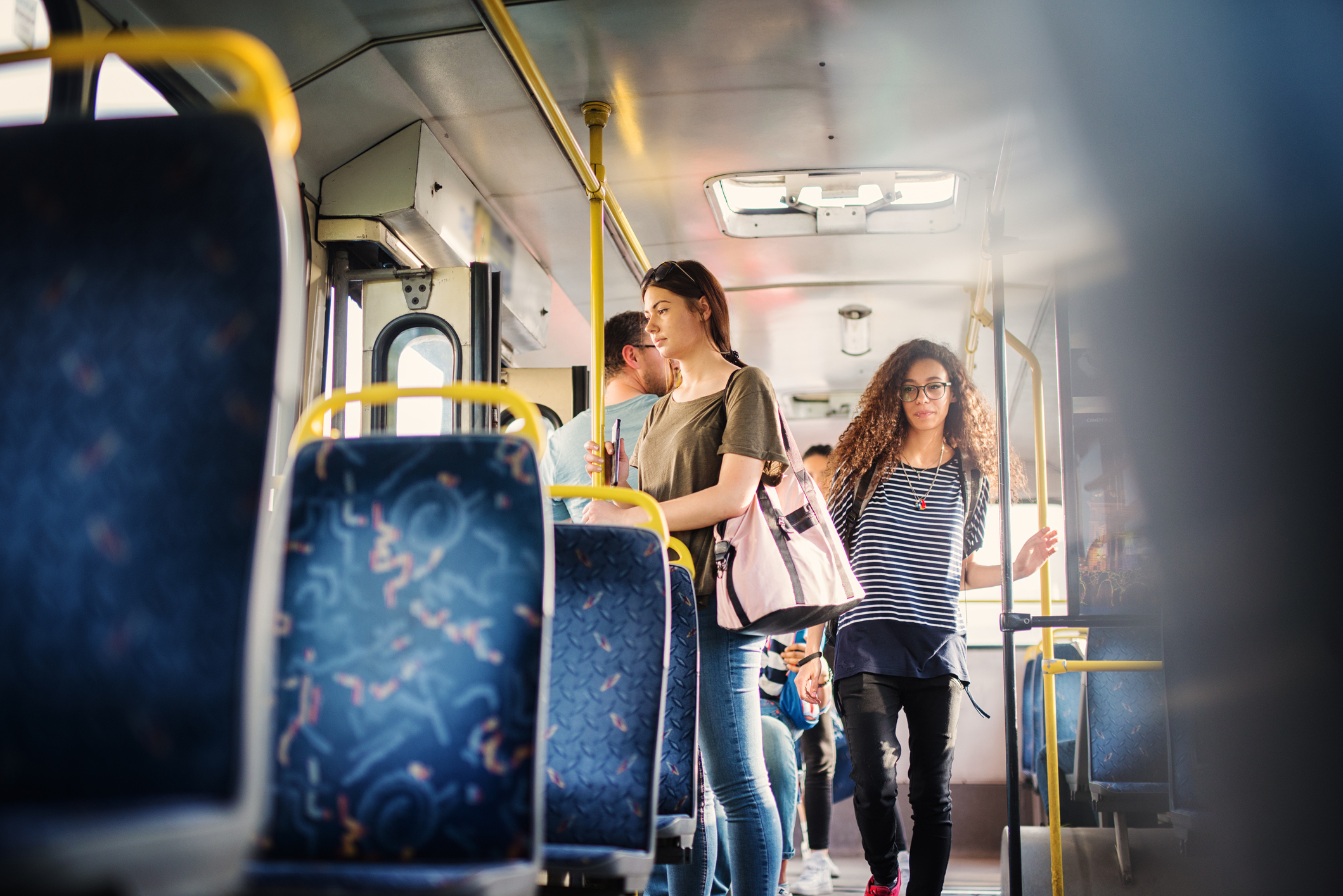 Curly girl is passing through the bus and trying to find a free seat. Curly girl is passing through the bus and trying to find a free seat.
