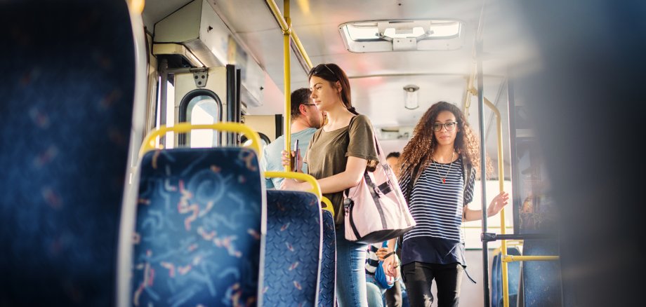 Curly girl is passing through the bus and trying to find a free seat.