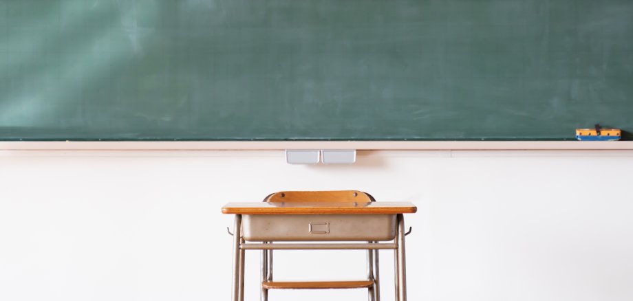 An image of a Japanese elementary school classroom with a blackboard and desk