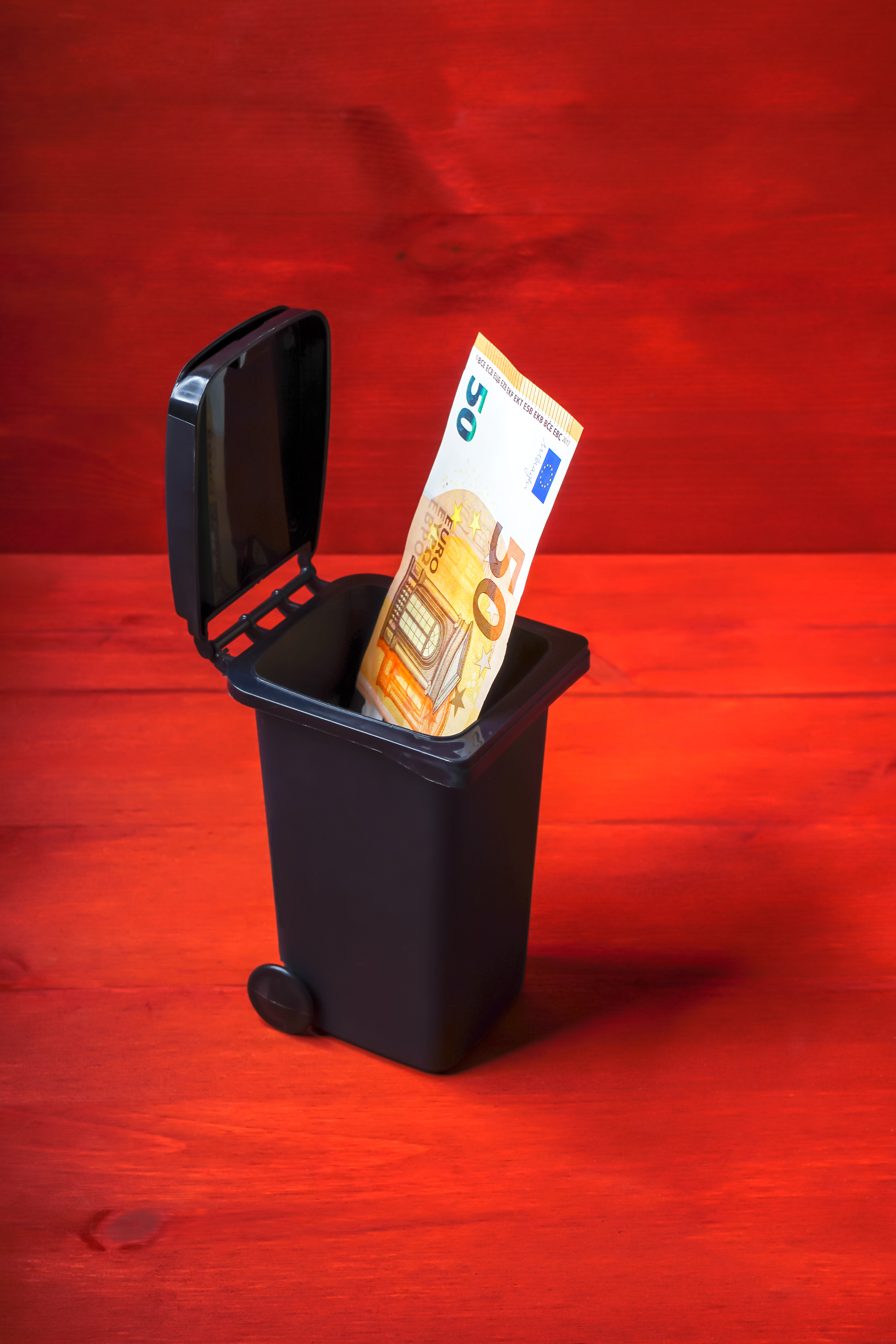 Euro banknote in a garbage can as a symbol of garbage fees, waste of money Euro banknote in a garbage can as a symbol of garbage fees, waste of money