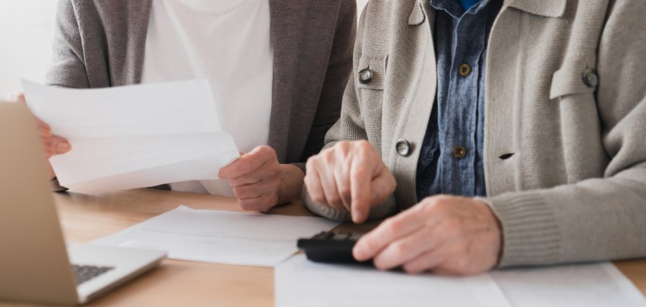 Serious caucasian old elderly senior couple grandparents family counting funds on calculator, doing paperwork, savings, paying domestic bills, mortgage loan, pension at home using laptop.