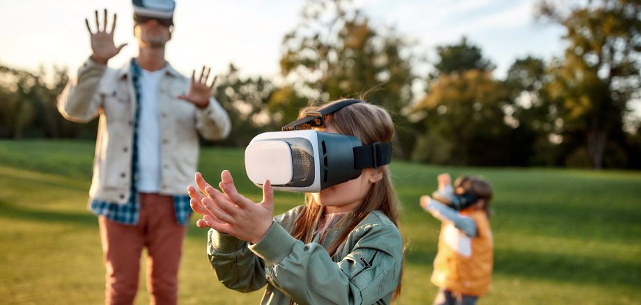 Something new. Family playing in virtual reality glasses outdoors