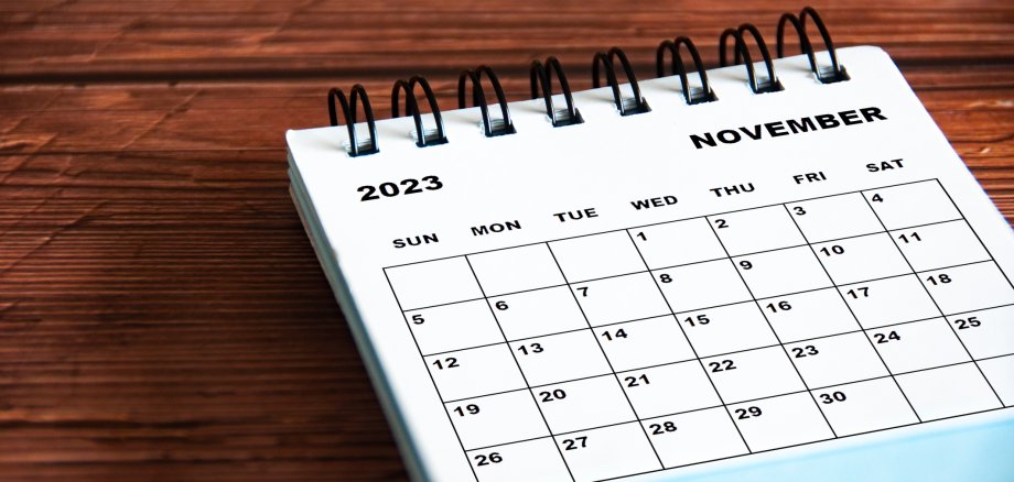 November 2023 white desk calendar on wooden table background. Calendar concept and copy space