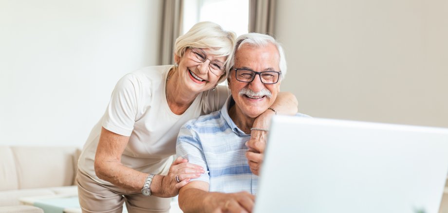 Elderly spouses at home. Wife hugs husband.Having pleasant conversation chatting with grown up children and grandchildren using wireless tech concept