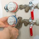 Male plumber fixing water meter with adjustable wrench.