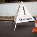 Warning sign and a traffic cone on the street
translation: Sewer works