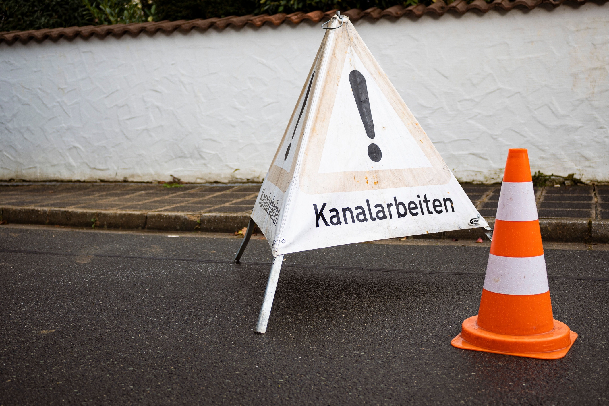 Warning sign and a traffic cone on the street
translation: Sewer works Warning sign and a traffic cone on the street
translation: Sewer works
