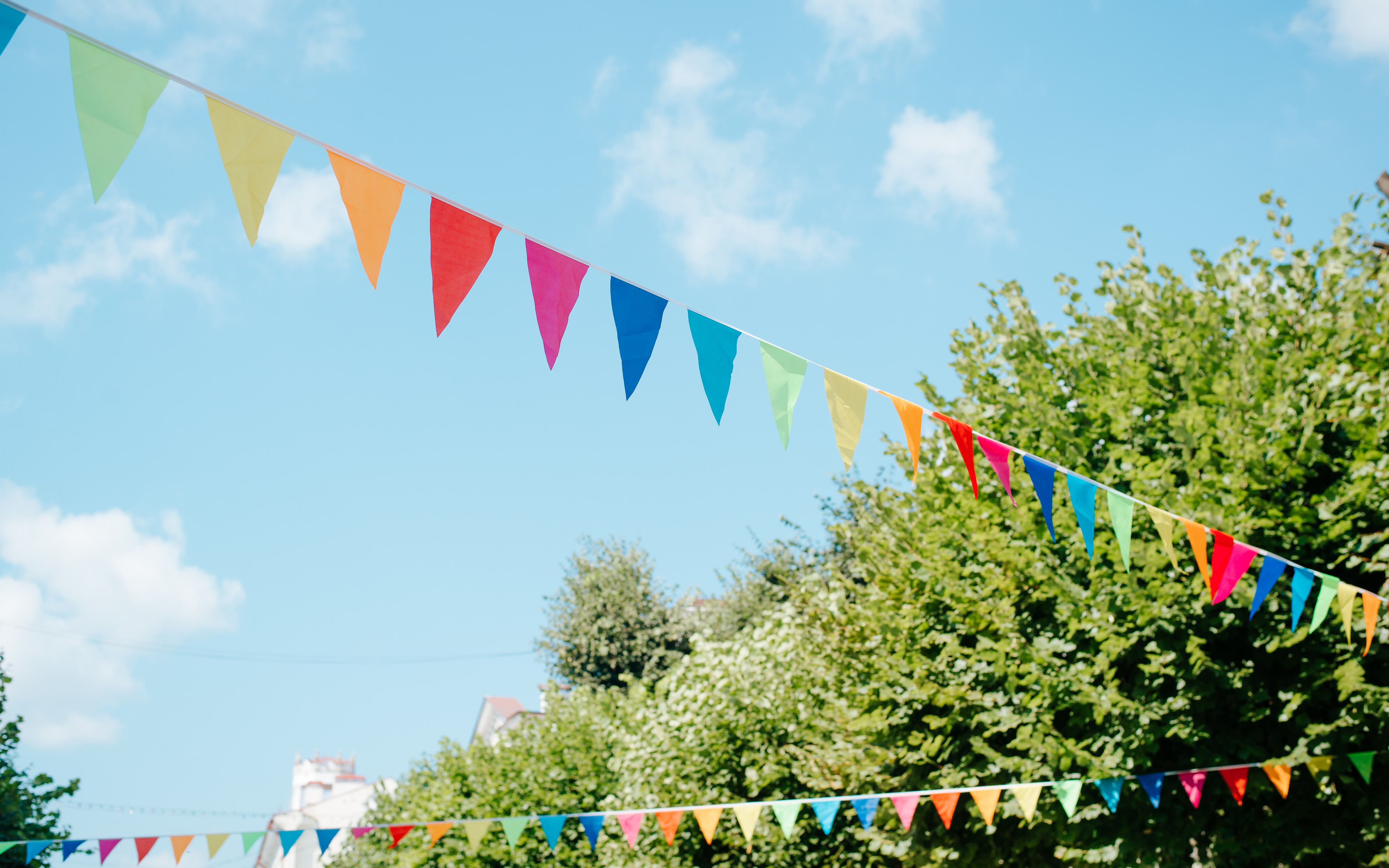 City festival event in park, street decorated with colorful triangular flags on sunny summer day against sky City festival event in park, street decorated with colorful triangular flags on sunny summer day against sky