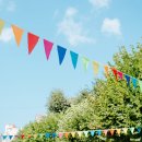 City festival event in park, street decorated with colorful triangular flags on sunny summer day against sky City festival event in park, street decorated with colorful triangular flags on sunny summer day against sky