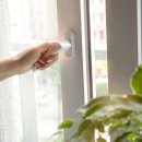 Woman's hand at home opening the white plastic window door. Room airing with fresh air. Ventilation concept.