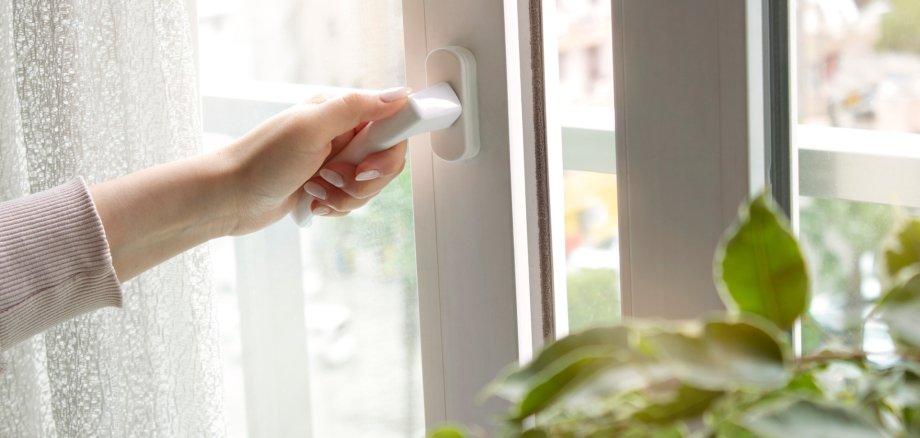 Woman's hand at home opening the white plastic window door. Room airing with fresh air. Ventilation concept.