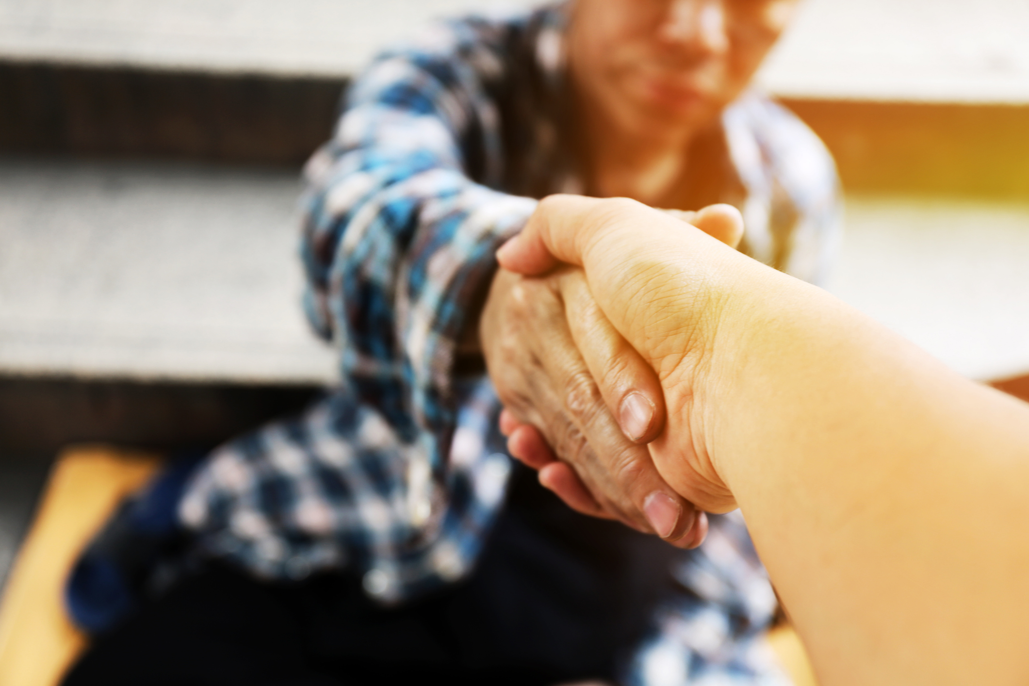 Close-up handshake for help homeless man on walking street in the capital city. Close-up handshake for help homeless man on walking street in the capital city.