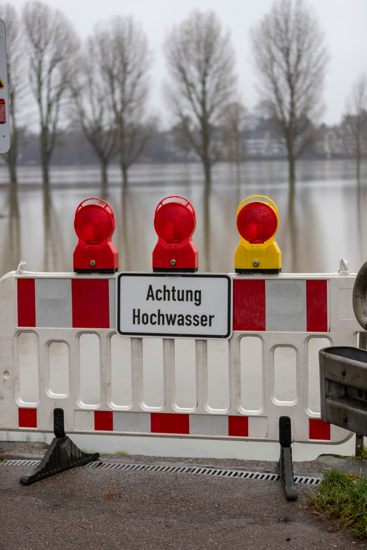 barrier blocking a way to the edge of rhine river, sign with german letters meaning caution high water, flood barrier blocking a way to the edge of rhine river, sign with german letters meaning caution high water, flood