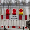 barrier blocking a way to the edge of rhine river, sign with german letters meaning caution high water, flood