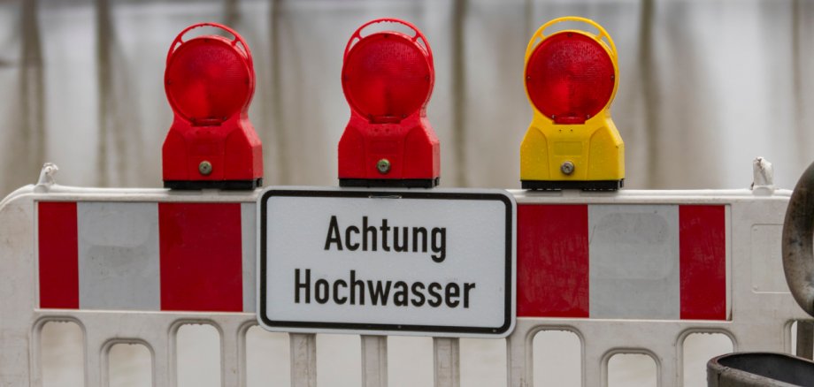 barrier blocking a way to the edge of rhine river, sign with german letters meaning caution high water, flood