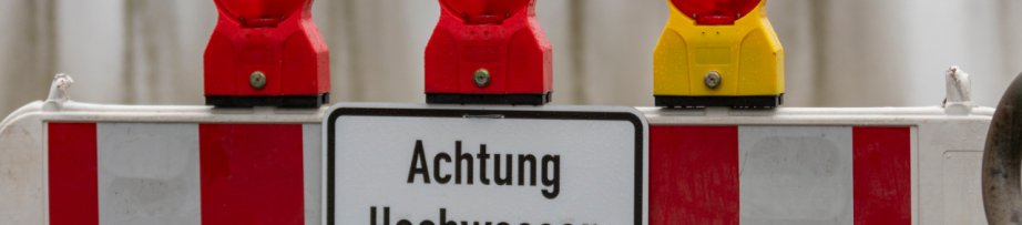 barrier blocking a way to the edge of rhine river, sign with german letters meaning caution high water, flood
