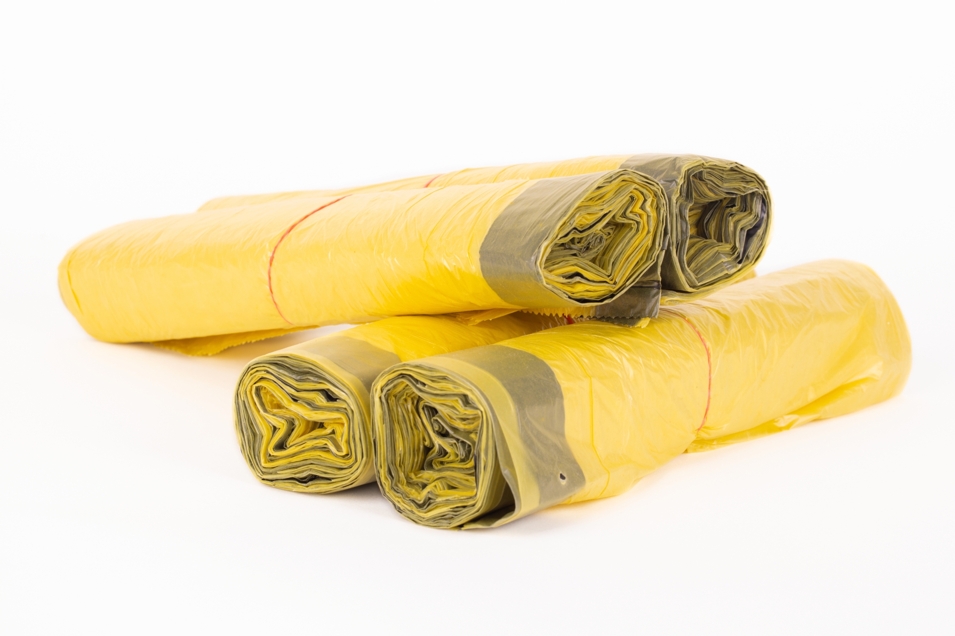 Rolls of yellow trash bags on white background