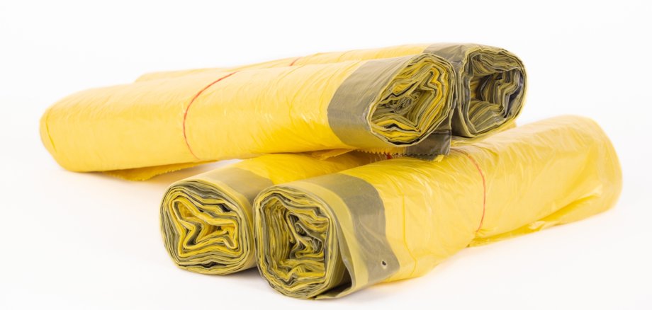 Rolls of yellow trash bags on white background