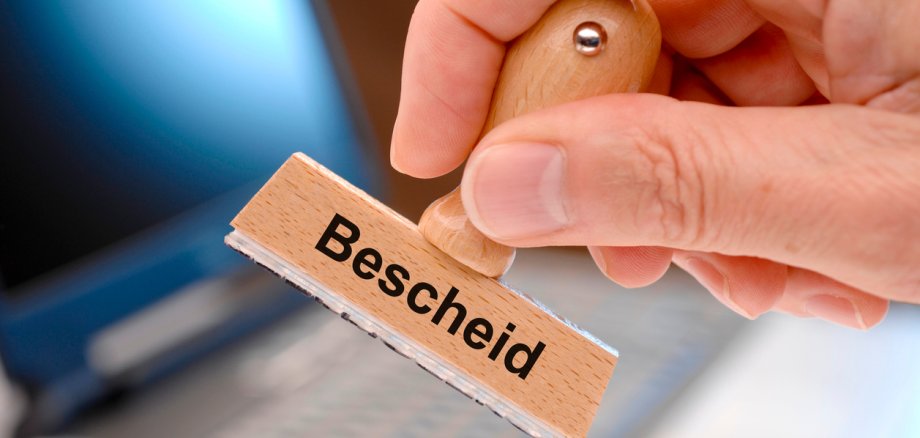 notification printed on rubber stamp in hand - in German language: Bescheid